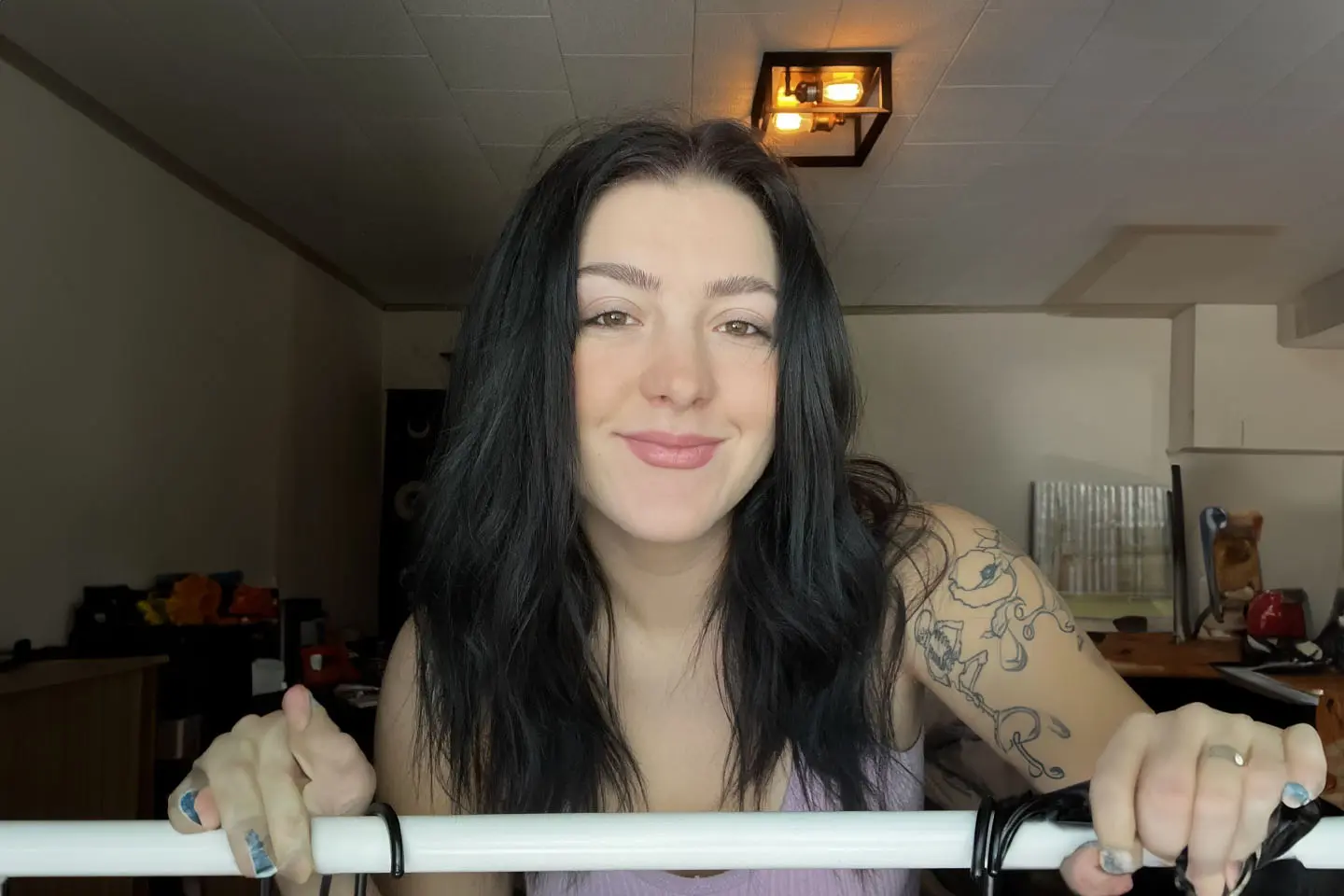 A woman with long black hair and tattoos is smiling.