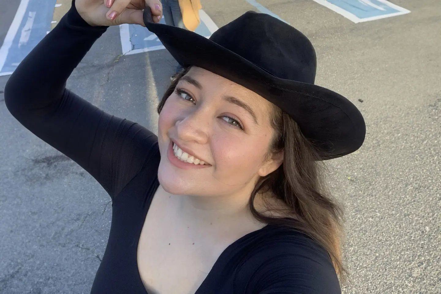 A woman in black shirt and hat smiling for the camera.